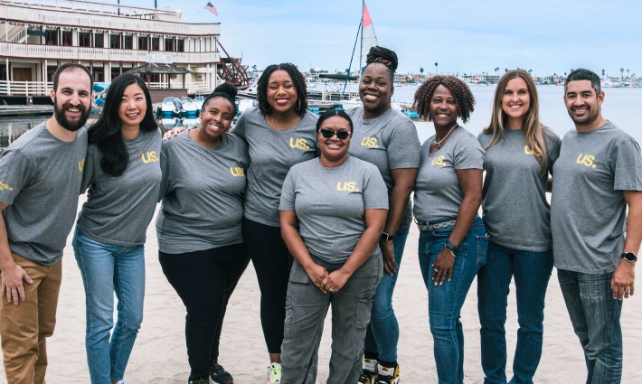Th Human Resources team gathers together at a company event, all wearing the same t-shirt and smiling.