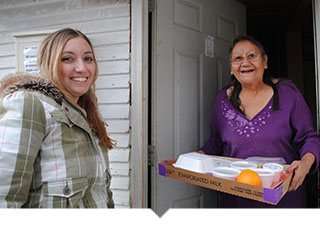 Volunteer delivers meal to older adult woman at her home