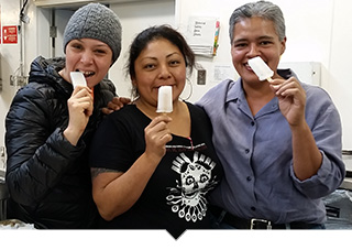 Three woman from Prospera Coop posing with funny faces eating popsicles