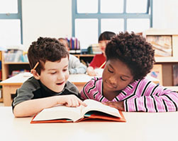 Photo of two boys reading from the same book