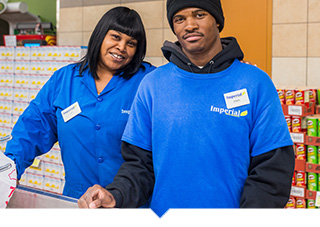 Two Imperial Fresh Market workers posing together inside grocery store in Detroit