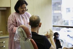 A dentist converses with her patient in an exam room