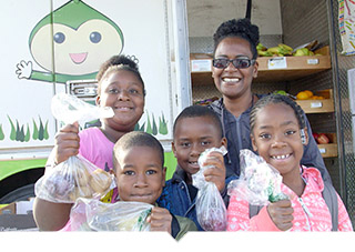 Family holds up bags of fresh fruit and vegetables