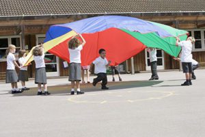 Young children playing with a parachute in the school playground