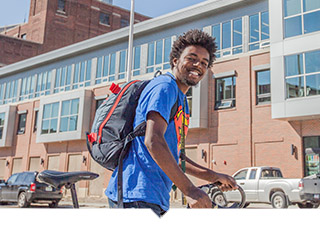 Young Man poses with bike outside of affordable housing complex