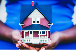 Close up of hands holding a model of a house