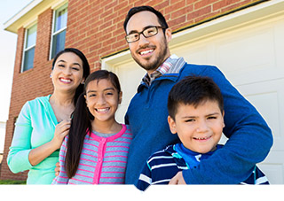 Mother and father with pre-teens pose in front of their home