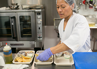 itchen worker prepares meals for delivery