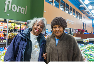 Two older women shop for produce