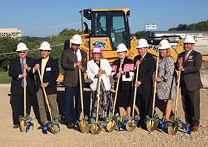 A group of people stand with shoves at the Health Services of North Texas clinic groundbreaking.
