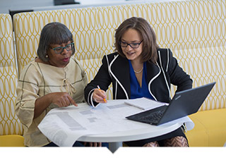Two women review papers at desk