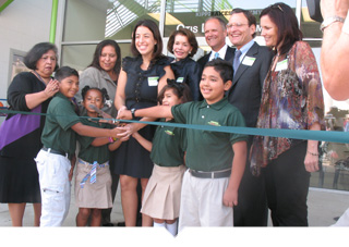 A group of adults and charter elementary school students cut the ribbon to celebrate a new school opening