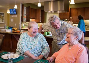 Health care professionals joke with senior patients.