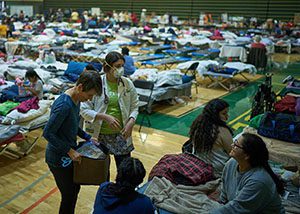 Medical staff consult with patients throughout an evacuation center.
