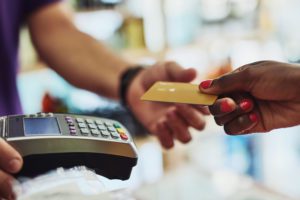 A woman hands a man her credit card.