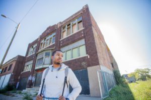 Young man in front of a boarded-up building