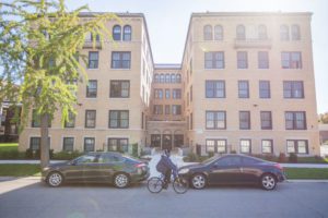 Man rides his bike past a renovated historic building