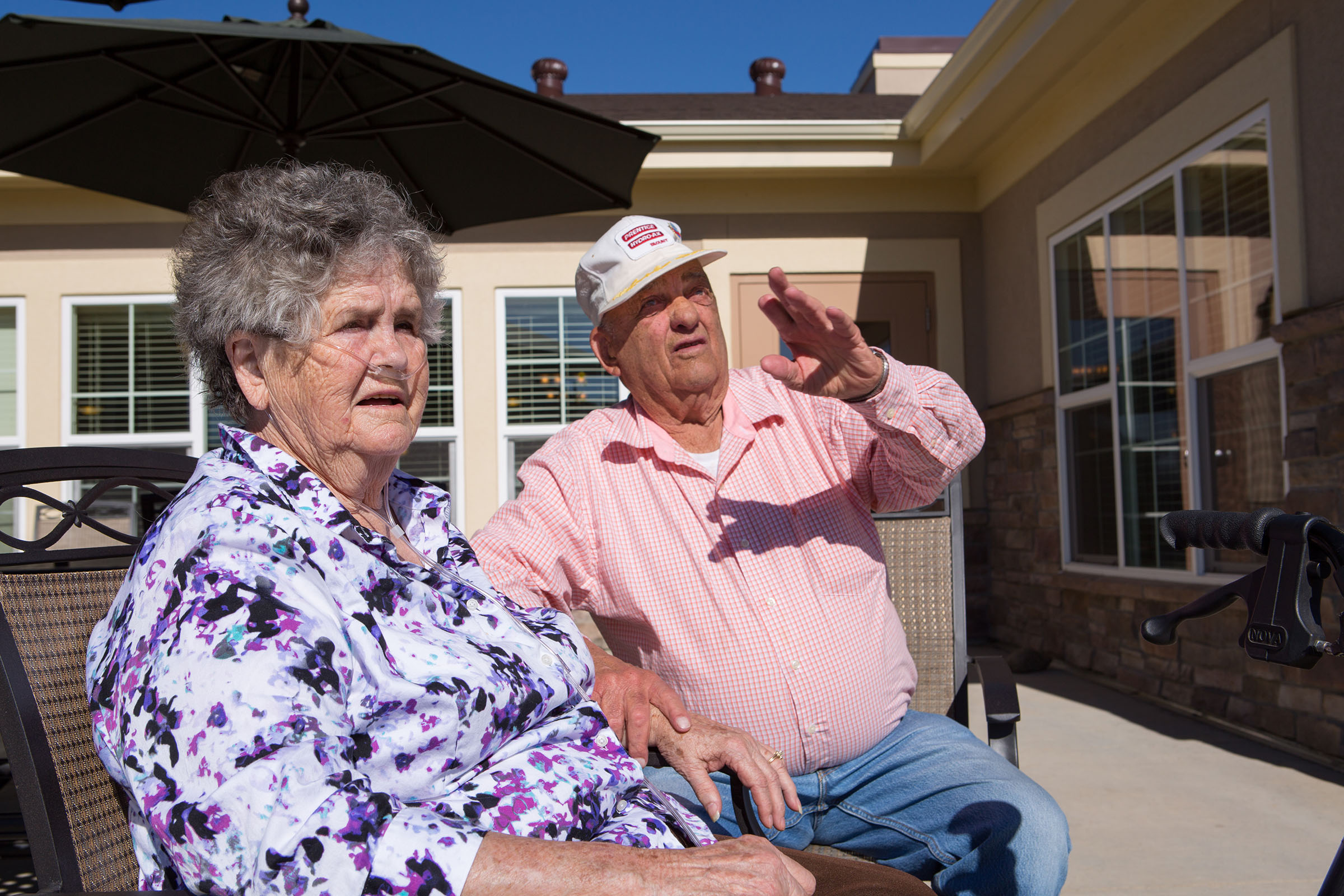 An older woman and man sit outside on the patio