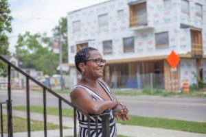 Woman smiles in front of construction at The Coe at West Village