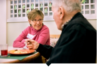 Nurse speaks with older adult patient at table