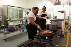 Women cook food as part of their cooperative business