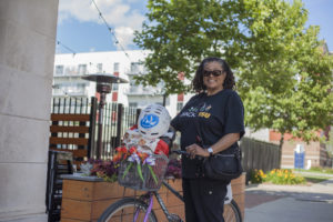 A woman stands in front of her Detroit apartment building.
