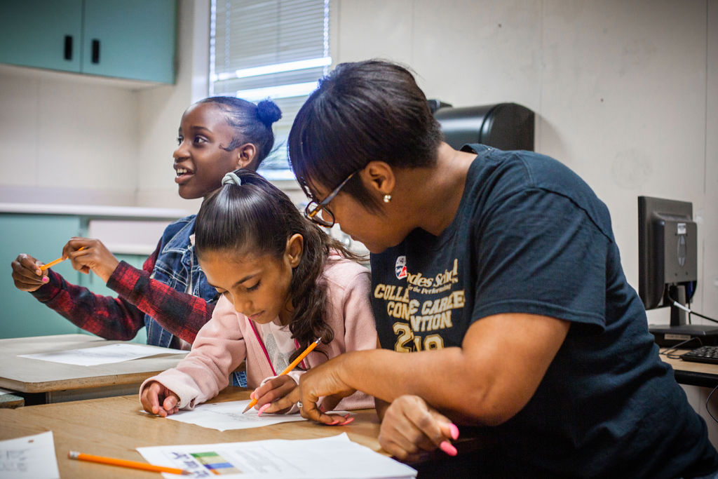 Teacher works with students at desks