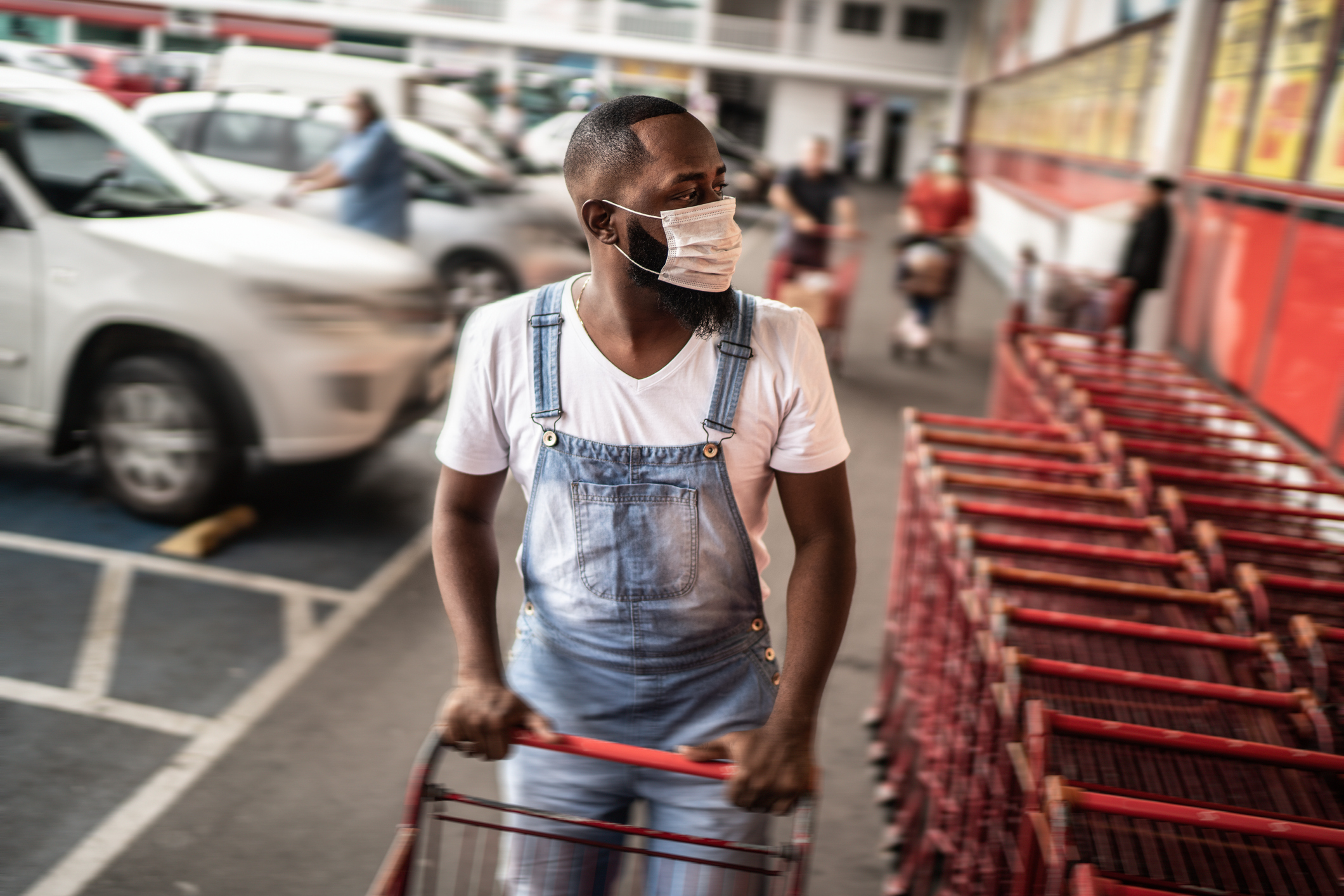 Men wearing face mask picking shopping cart in supermarket