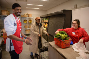 Market staff help woman shop for groceries