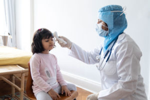 Doctor takes temperature of little girl