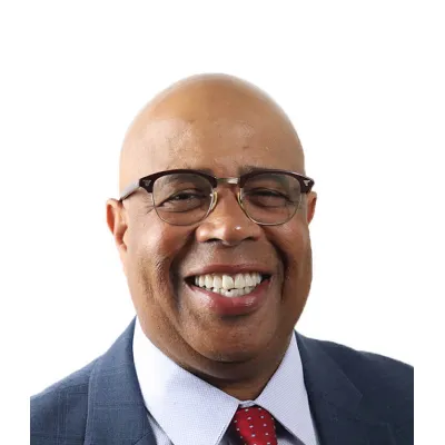Gary Cunningham, shown smiling, wearing glasses, a blue suit, white dress shirt, and red tie.