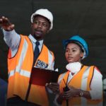 Man holds blueprint at a construction site.