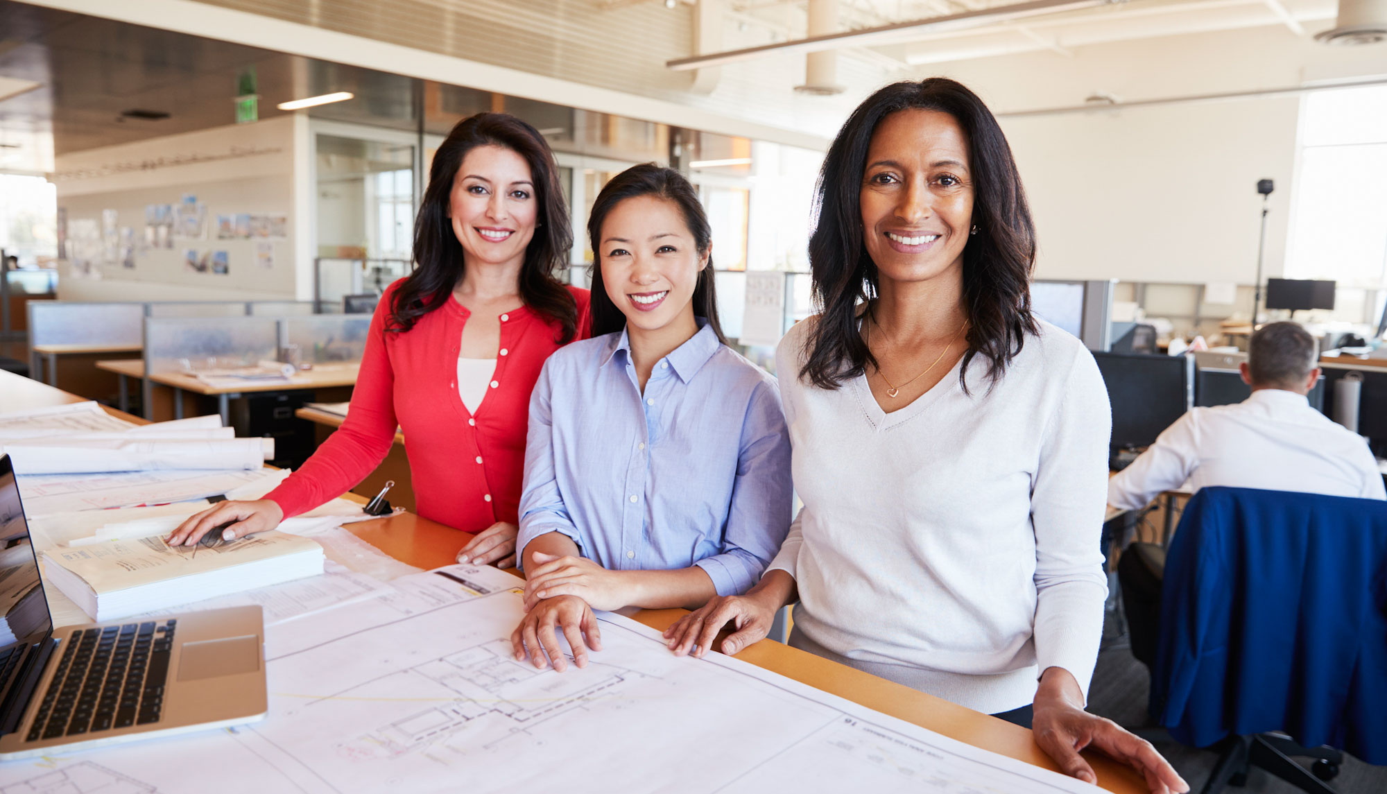 Three female architects working together look to camera