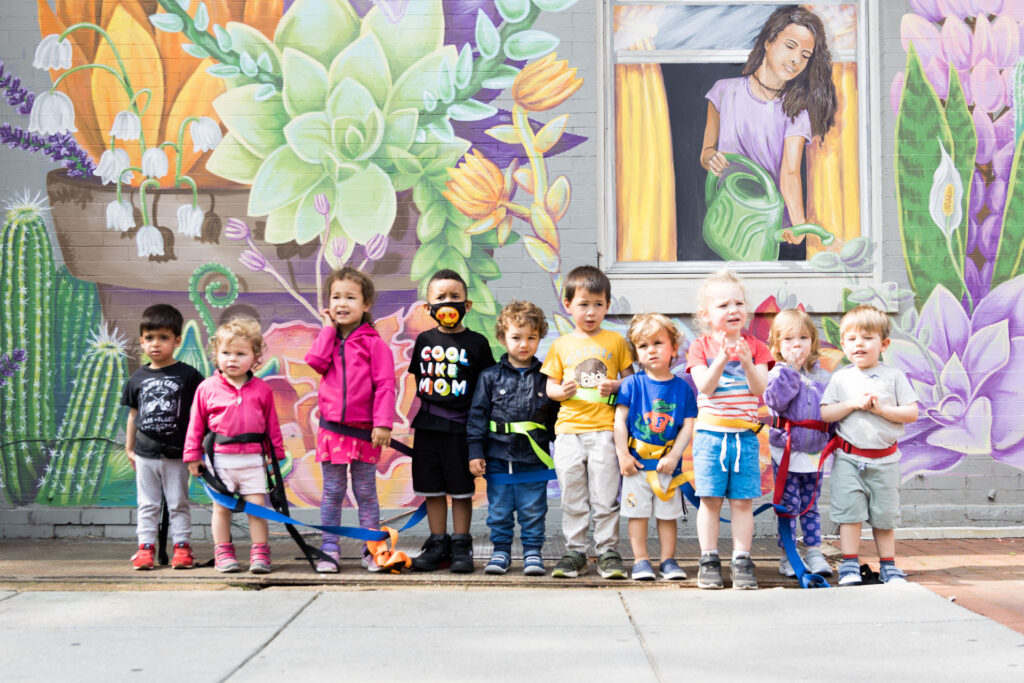 Children stand in front of a sidewalk mural