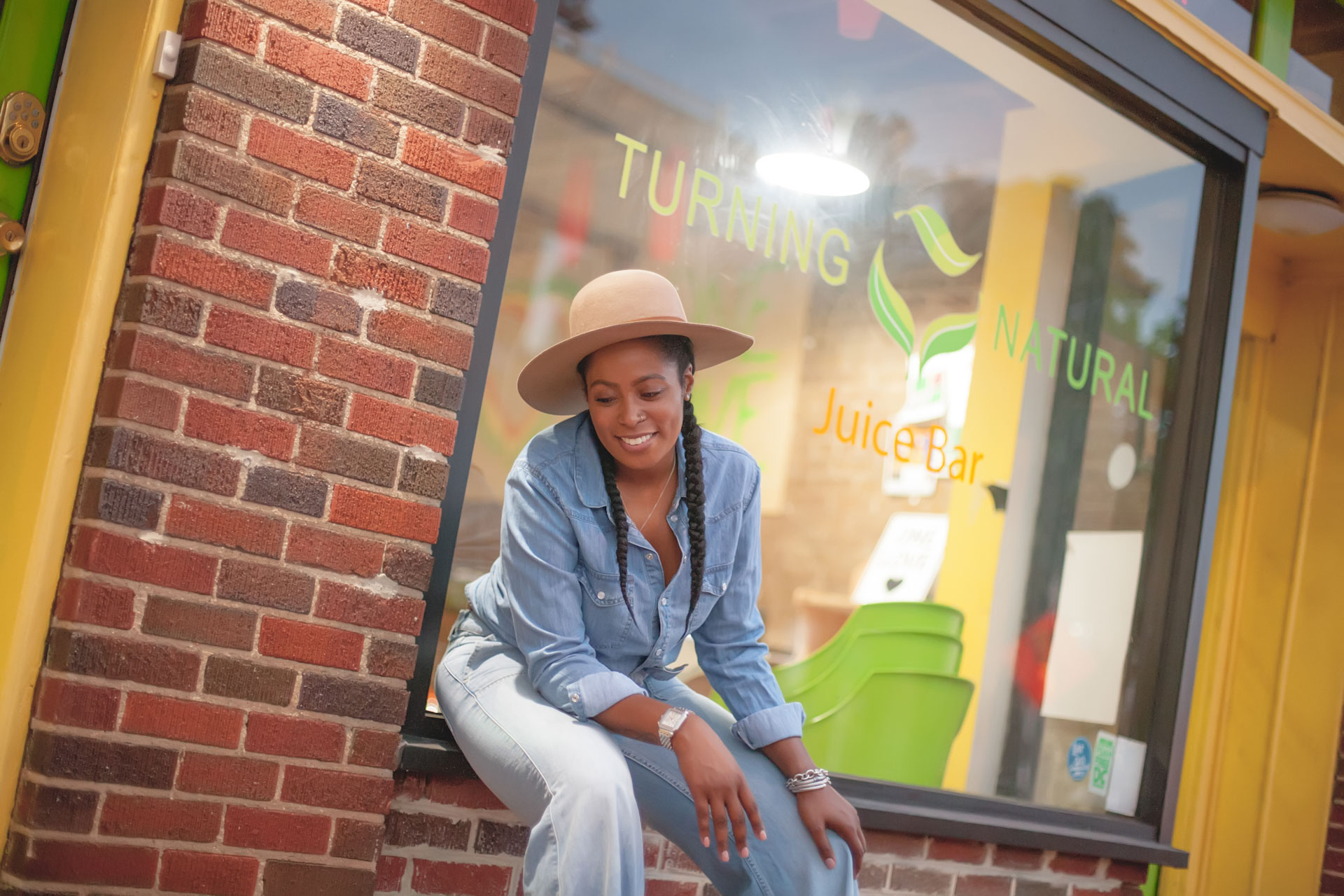Women wearing hat sitting in front of Turning Natural Juice Bar in Washington, DC, a business which recieved a 2021 Nourish DC grant