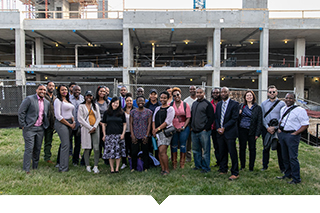 A group of developers of color stand in front of a construction site