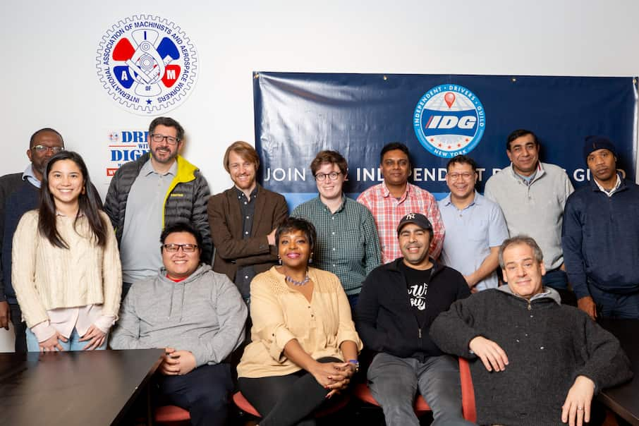 Independent Drivers Guild members pose together as a group in front of their signage.