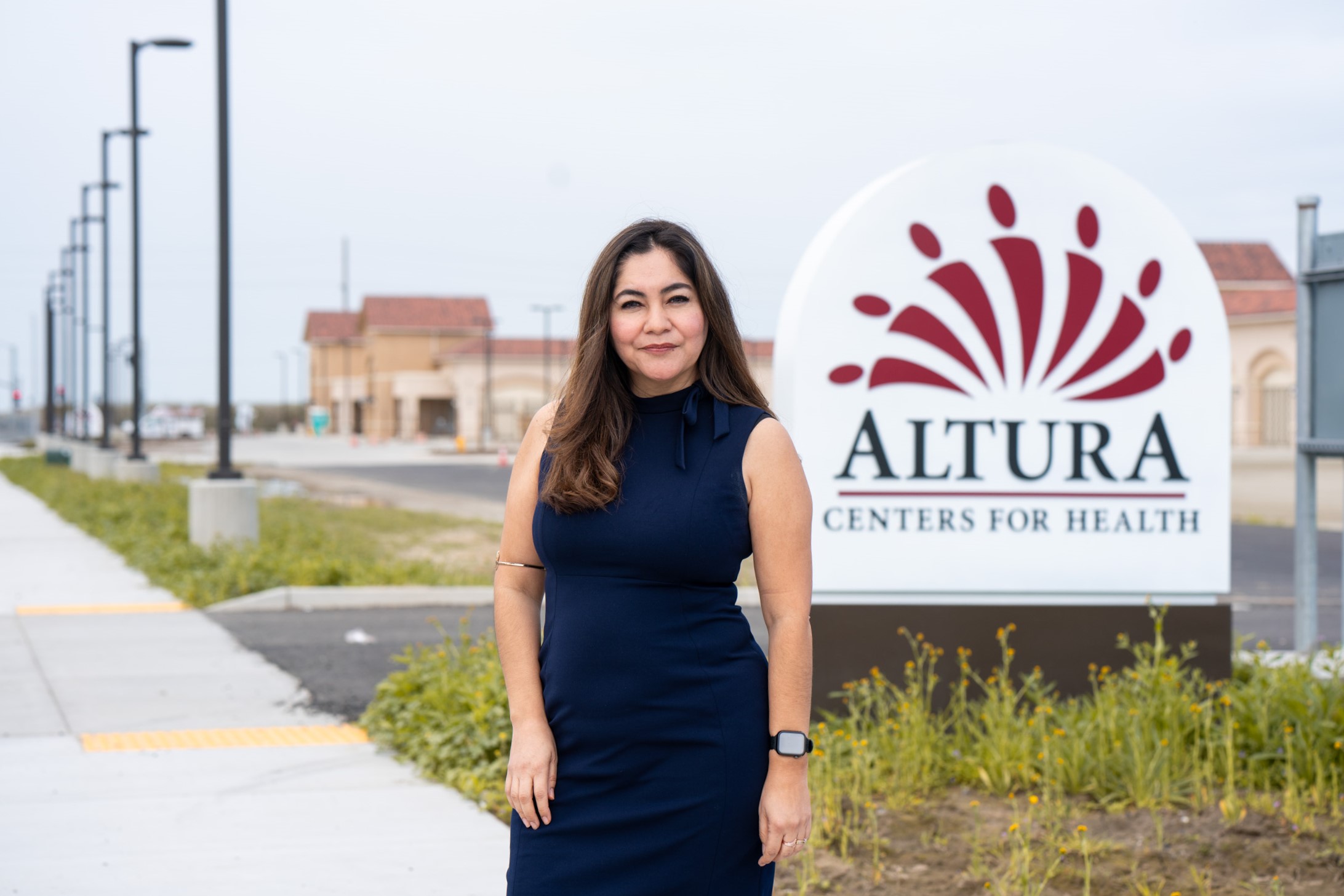 Graciela Soto Perez, chief executive officer at Altura Centers for Health in Tulare County smiles at the camera while standing in front of a sign saying 'Altura Centers for Health'