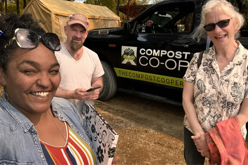 Members of the Compost Cooperative, one of Capital Impact Partner's Co-op Innovation 2023 Award winners, pose in front of a banner saying 'Compost Co-op'.
