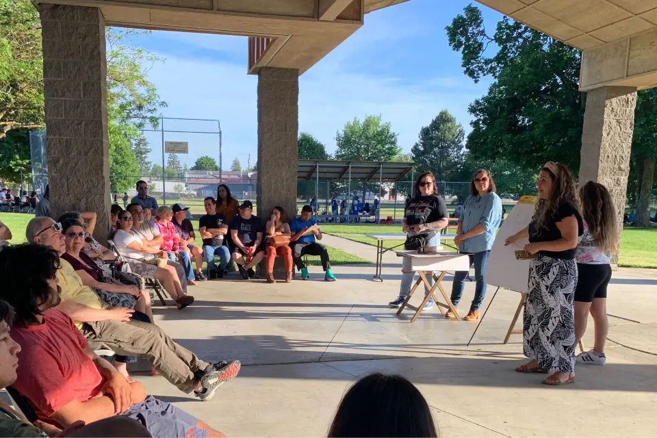 Four women from Northwest Cooperative Development Center, a 2023 Co-op Innovation awardee, presenting to a seated audience outdoors.