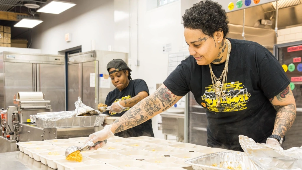 Two women in a commercial kitchen preparing healthy meals, representing ChiFresh Kitchen's commitment to community and quality food.
