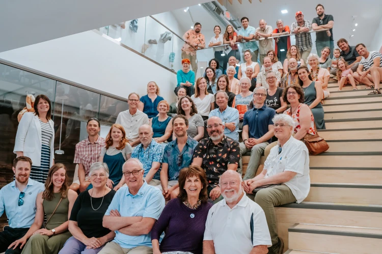 A large group of the members of the Commongrounds Cooperative, one of Capital Impact Partner's Co-op Innovation 2024 Award winners, pose together on a large staircase in an open area.