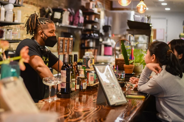 An employee of Montana Cooperative Development Center, one of Capital Impact Partner's Co-op Innovation 2024 Award winners, serve two customers from behind a register.