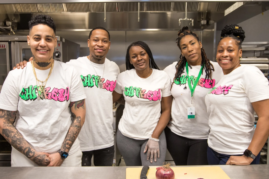 Employees of ChiFresh Kitchen, wearing matching t-shirts collaborate, embodying the spirit of community and cooperative business models.
