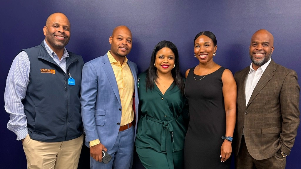 Five graduates stand proudly in front of a blue wall, celebrating their completion of the 2025 EDI Real Estate Development Program in Atlanta.