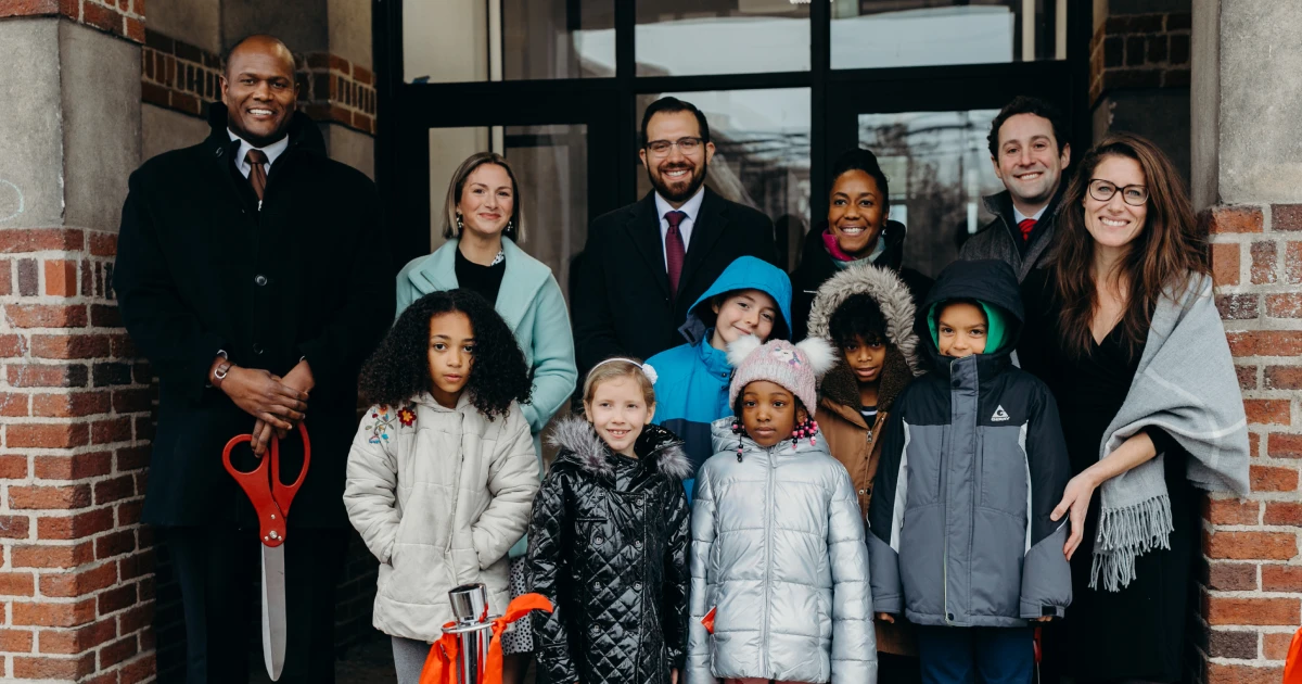 Students and staff smile at the camera after the ribbon cutting of a charter school facility financed by Capital Impact Partners.