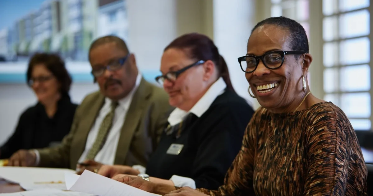 Executives and advisors reviewing facility plans to improve community health center loan eligibility.