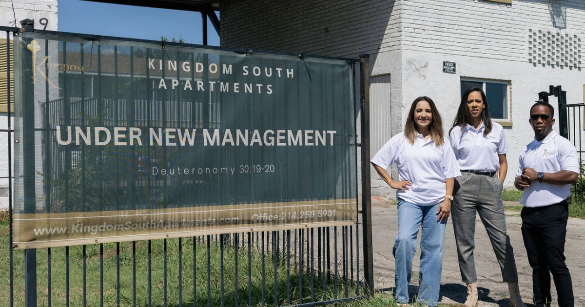 Three team members from Kingdom Legacy stand in front of the Kingdom South Apartments in Dallas, recently acquired and revitalized with financing and support from Momentus Capital.