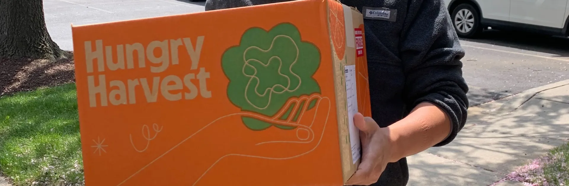 Person holding a Hungry Harvest produce box for healthy food delivery programs supported by mezzanine financing from Momentus Capital.